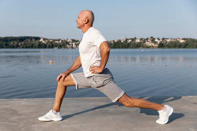 Elder in sportswear stretching outdoors