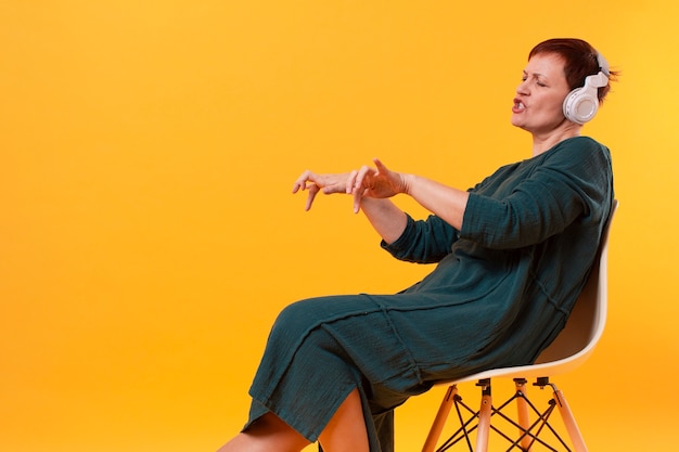 Elder woman on chair listening music and dancing