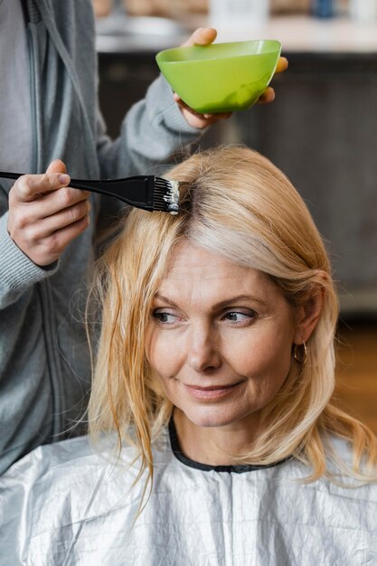 Elder woman getting her hair dyed by hairdresser at home