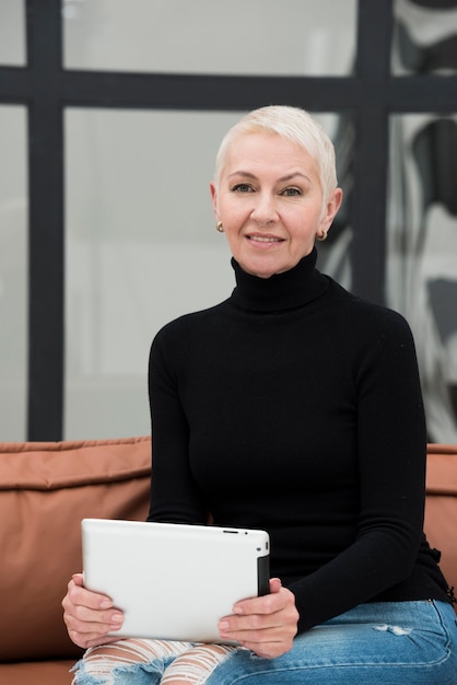 Elder woman sitting on couch whole holding tablet