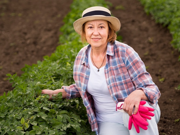 Elder woman staying next to a plant in her garden