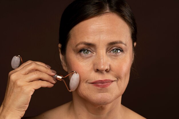 Elder woman using rose quartz roller on her face