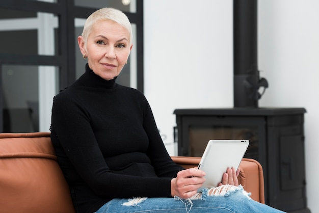 Elder woman with tablet relaxing on couch