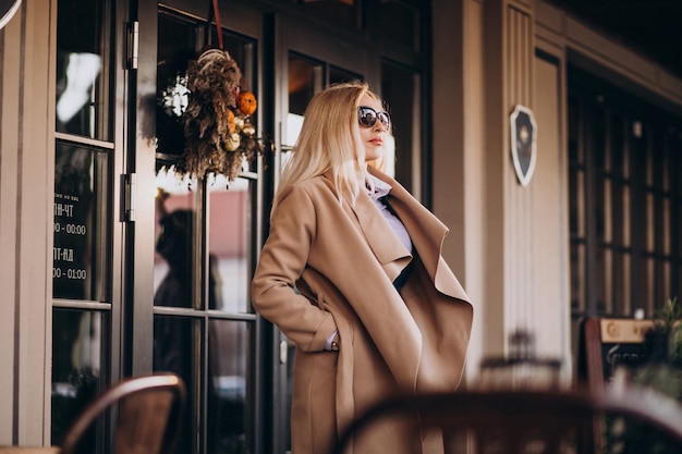 Elderly businesswoman in a coat outside the cafe