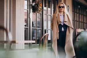 Free photo elderly businesswoman in a coat outside the cafe