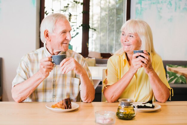 Elderly cheerful couple drinking tea and talking lively