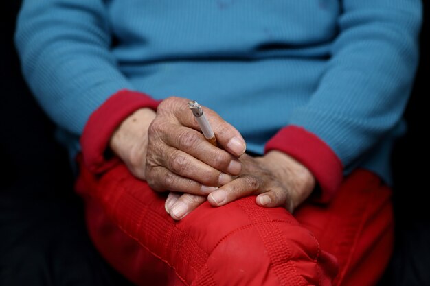 Elderly Chinese woman sitting and smoking- women empowerment concept