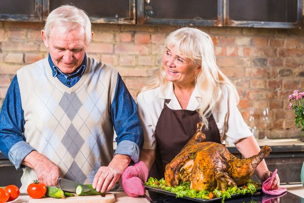 Elderly couple cooking turkey with vegetables