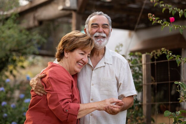 Elderly couple holding each other romantically at their countryside home garden