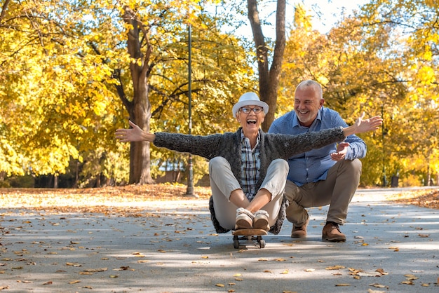 Elderly couple with a woman sitting on skate in the park