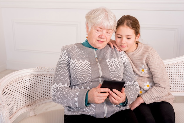 Free photo elderly grandma reading with her granddaughter