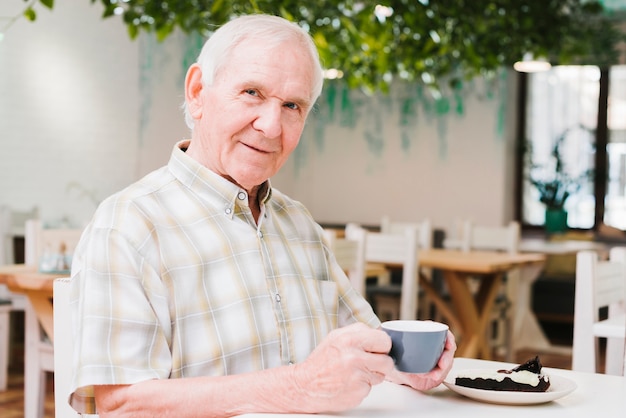 Elderly man drinking tea and looking at camera