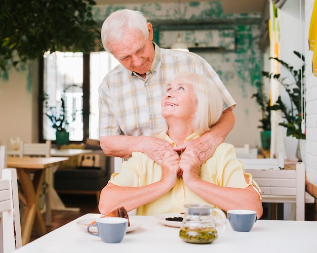 Elderly man embracing wife from behind