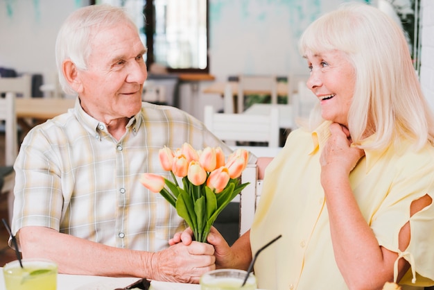 Free photo elderly man giving flowers to beloved