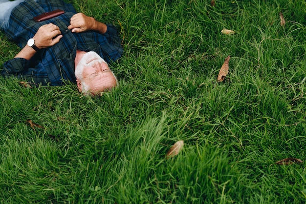 Free photo elderly man sleeping on green grass