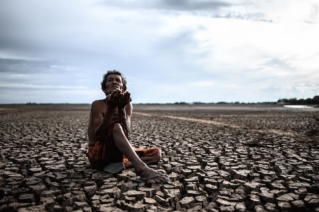 Free photo an elderly man was sitting asking for rain in the dry season, global warming