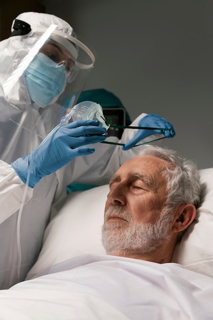 Elderly man with respirator next to doctors