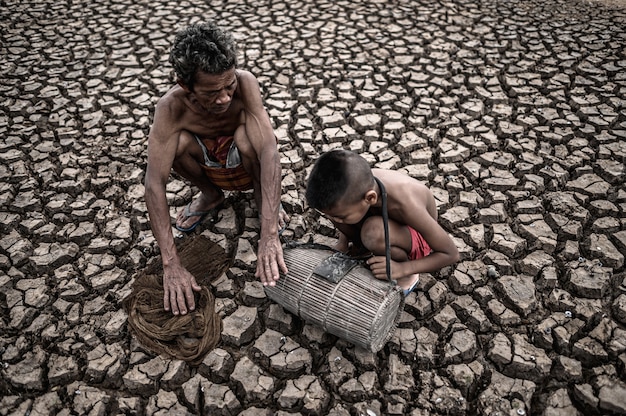 Elderly men and boy find fish on dry ground, global warming