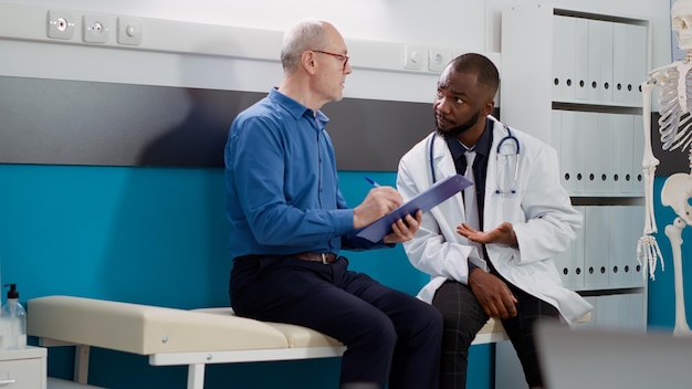 Free photo elderly patient signing consultation form to receive medication and prescription treatment. physician helping old man with disease to cure diagnosis at examination appointment.