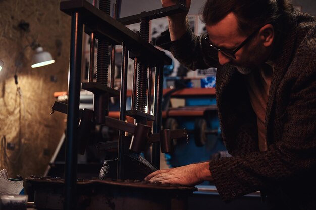 Elderly person is serving boot service at his own personal workshop.