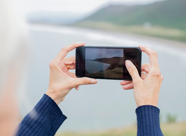 Elderly woman capturing a photo of the ocean