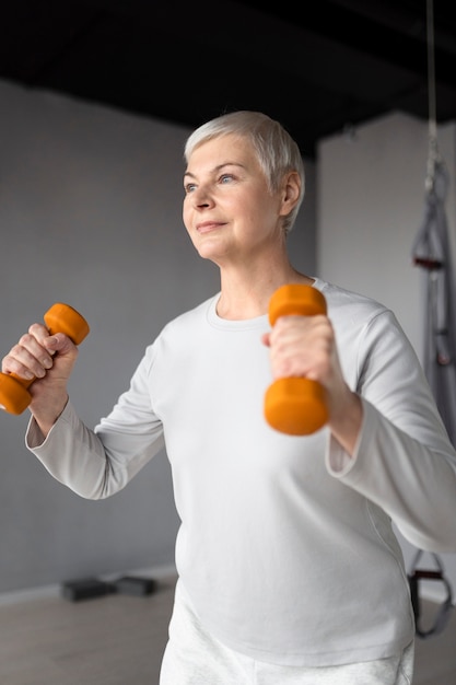 Free Photo elderly woman doing dumbbells exercises at the gym