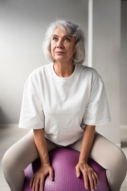 Elderly woman doing a gym ball workout at the gym