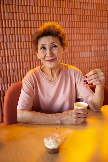 Free photo elderly woman drinking coffee at a cafe