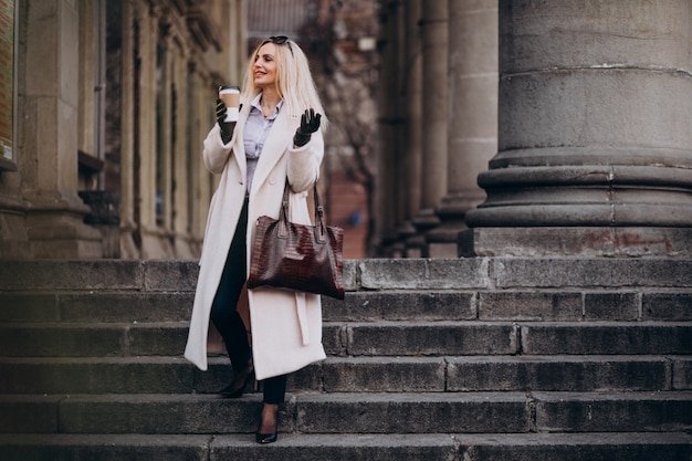 Free photo elderly woman drinking coffee outside the street