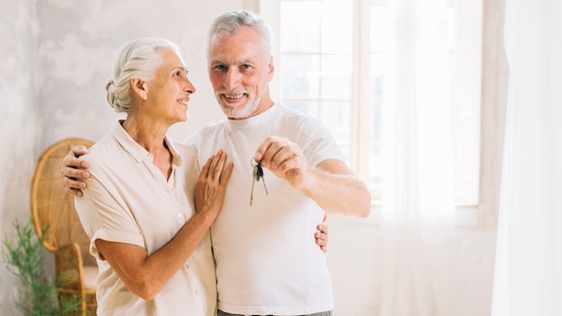 An elderly woman looking at her husband showing house key at home