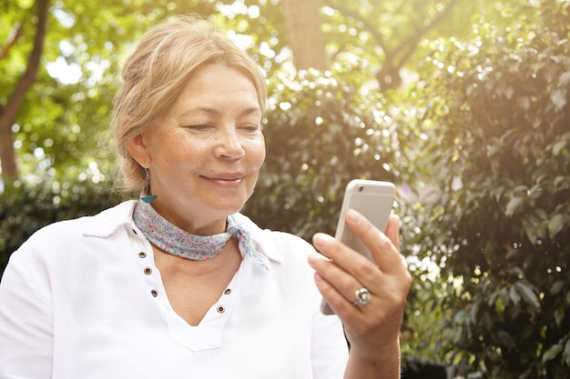 Elderly woman in park using phone