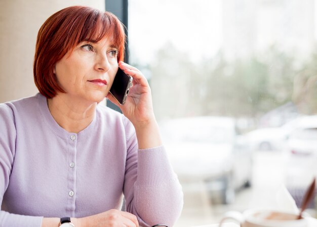 Elderly woman posing talking by phone