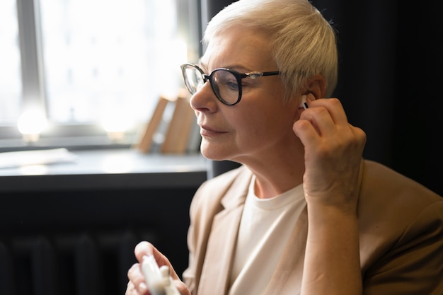 Elderly woman putting her headphones in her ears at a cafe