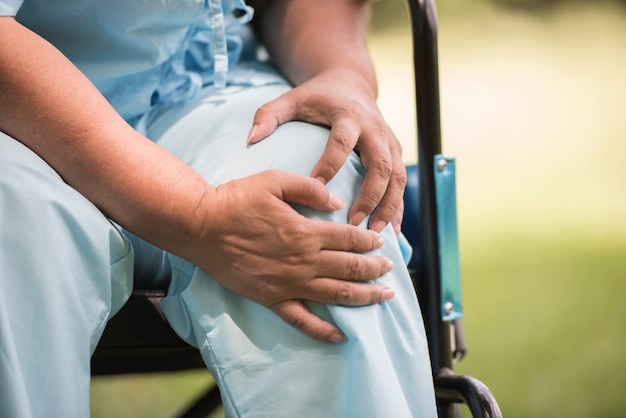 Elderly woman sitting on wheelchairs with knee pain