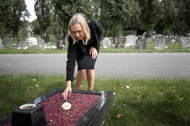 Free photo elderly woman visiting the grave of loved one