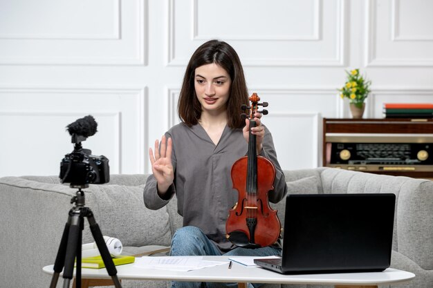 Elearning young cute beautiful girl remotely at home giving violin classes talking on camera