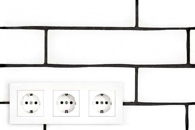 Free photo electrical outlets against a white brick wall.