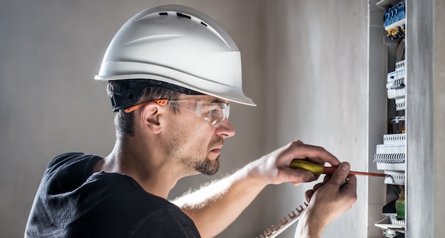 Free Photo electrical technician working in a switchboard with fuses. installation and connection of electrical equipment.