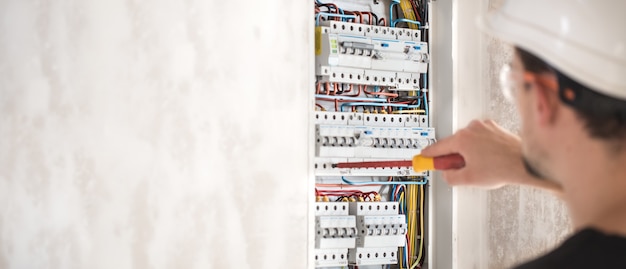 An electrical technician working in a switchboard with fuses