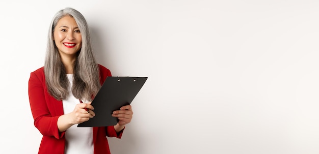 Free Photo elegant asian senior businesswoman working with documents holding pen and clipboard signing contract