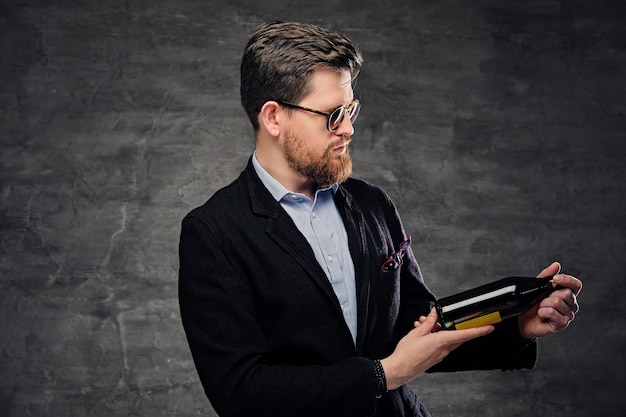 Free photo an elegant bearded male dressed in a cotton velvet jacket and sunglasses holds craft bottled beer.