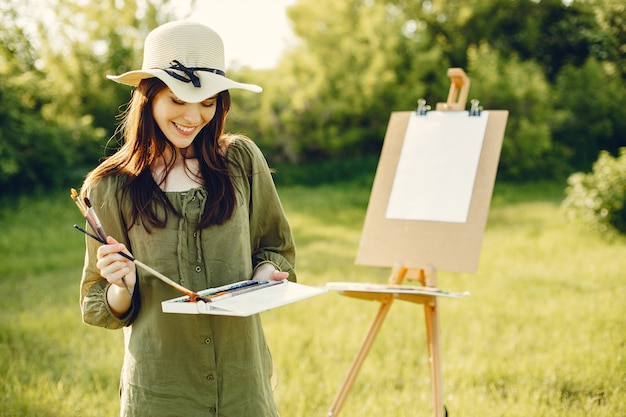 Elegant and beautiful girl painting in a field