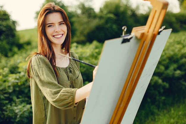 Elegant and beautiful girl painting in a field