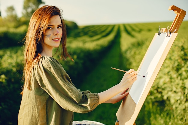 Free photo elegant and beautiful girl painting in a field