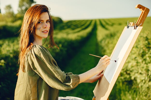 Elegant and beautiful girl painting in a field