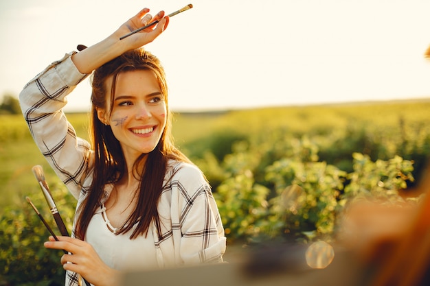 Elegant and beautiful girl painting in a field