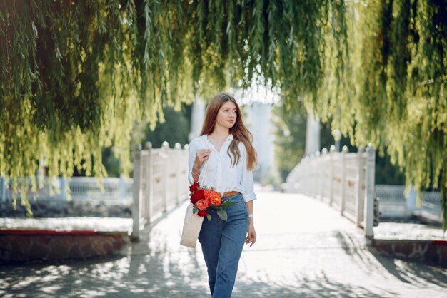 Elegant blonde in a summer park with flowers