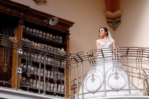 Free photo elegant brunette bride standing on balcony indoors