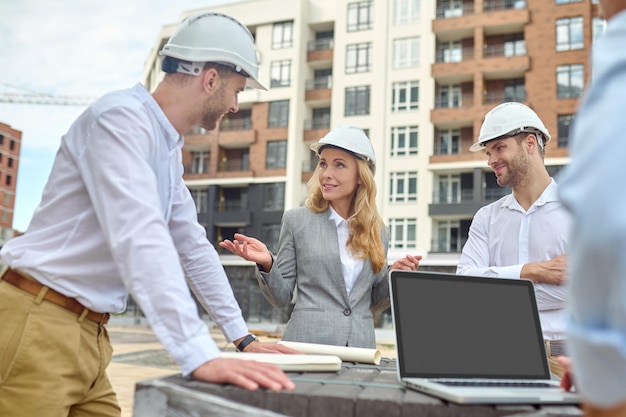 Elegant building supervisor talking to builders outside