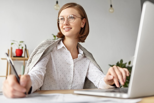 Free Photo elegant businesswoman dressed formally sitting with laptop